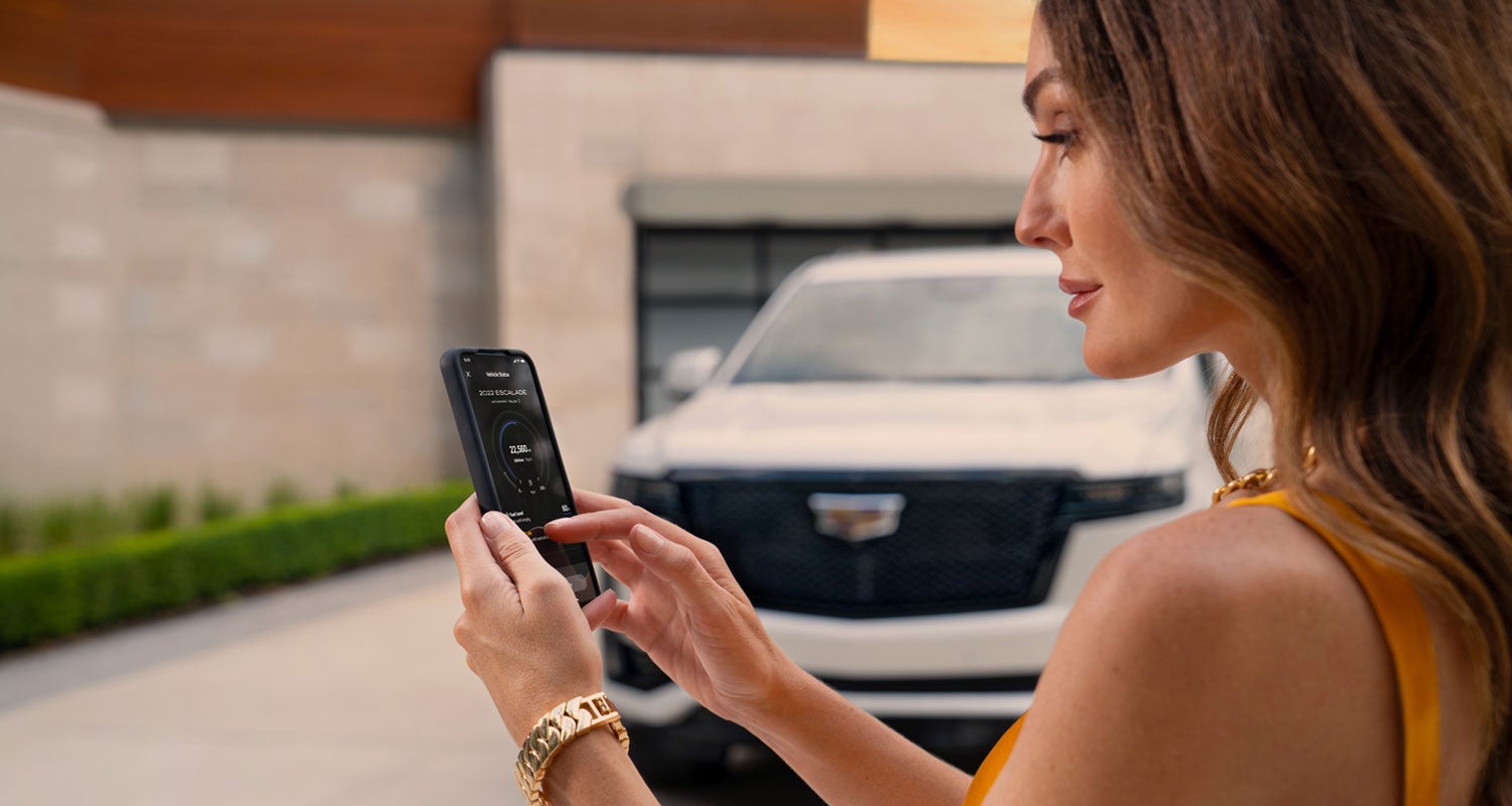 lady checking her mobile with a Cadillac vehicle background | Braden Cadillac in CARROLL OH